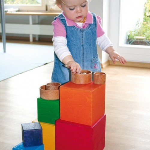 Grimms koka kastes lielās varavīksnes krāsās ar bērnu rotaļā